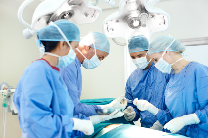 Surgeon receiving assistance from medical staff while operating on a patient